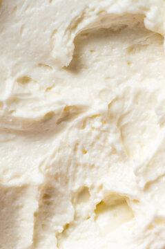 Close-up of fluffy, white whipped cream or buttercream frosting with soft peaks and a smooth, creamy texture.