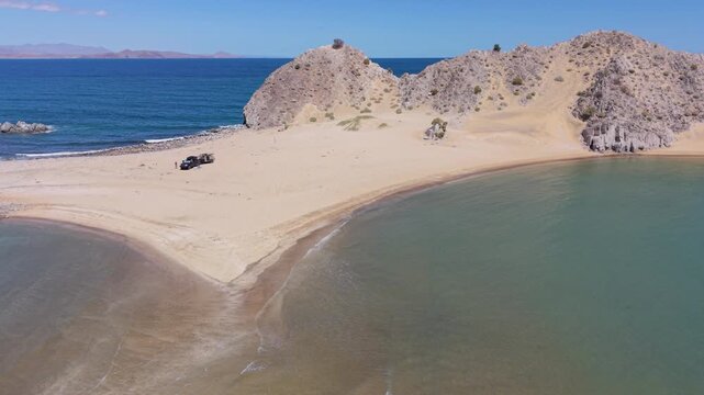 Aerial view showing an SUV with a teardrop camper trailer parked on an island beach at Punta Final in Baja California.