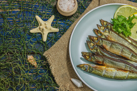 Smoked smelt with fresh lemon and herbs. Salted fish with marine decor. Trendy dish, sea rope