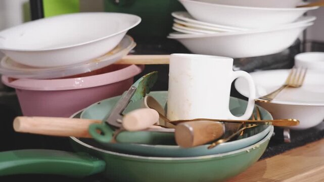 Messy kitchen counter with a huge pile of unwashed dirty dishes, pans, and cutlery