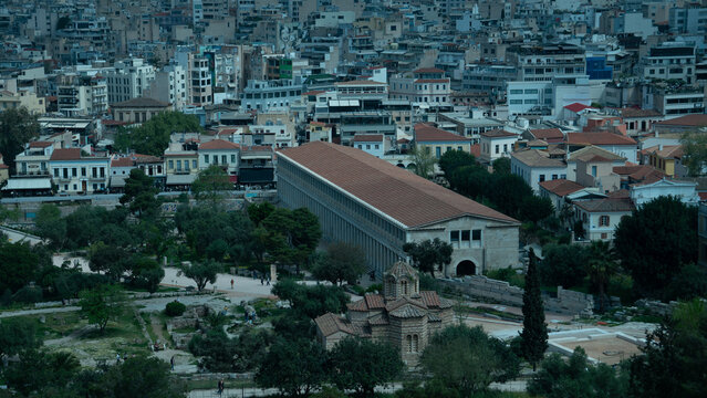 The Stoa of Attalos and Church of the Holy Apostles within the Ancient Agora contrast against the modern urban sprawl of Athens, Greece.