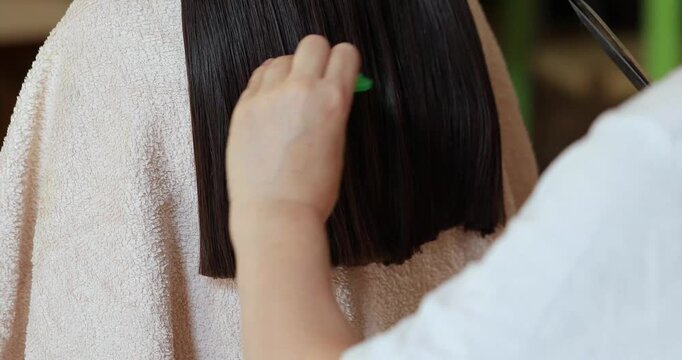Hairdresser cutting long dark hair with scissors