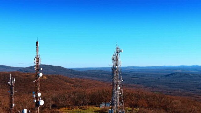 Mountainous landscape covered with forests in late autumn. Distancing from lattice towers located on the lawn.