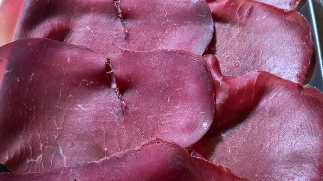 Bresaola della Valtellina, tracking shot with a close-up of slices of bresaola cured  meat viewed from above