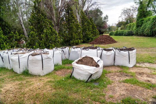 White bulk bags filled with soil and compost on grass, preparing for landscaping work