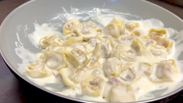 Tortellini pasta cooked in a nonstick pan with a creamy white sauce made with cream and cheese and ham
