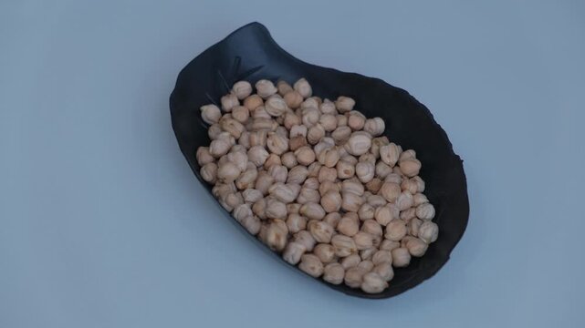 Top view of raw chickpeas or Kabuli Chana served in a black leaf-shaped plate