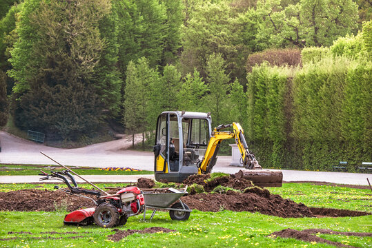 Landscaping works with mini excavator and garden tiller preparing soil 