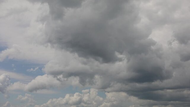 Timelapse of dark dramatic storm clouds moving across sky, moody overcast cloudscape with grey and white formations, weather change concept
