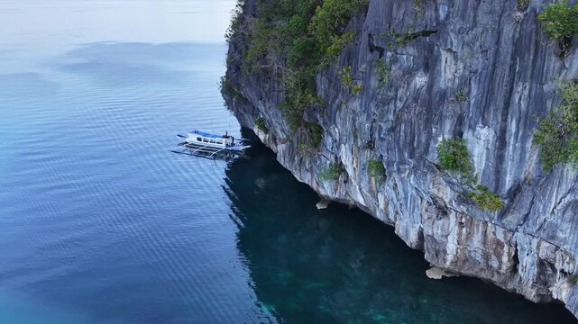 A small bangka drifts at the mouth of Cathedral Cave found in Pinisil Island, Philippines. This beautiful geologic marvel is a famous tourist attraction near El Nido, Palawan.