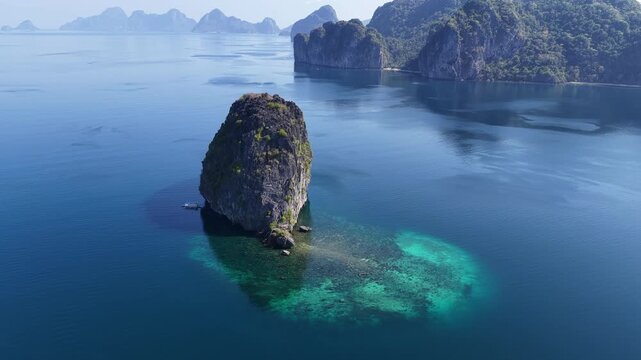 The dramatic Pinisil Island rises from Bacuit Bay, El Nido. This area in the Philippines is a popular vacation destination due to its beautiful coral reefs, beaches, and limestone islands.