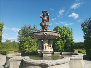 Obraz premium Baroque fountain with sculpture in formal garden under blue sky