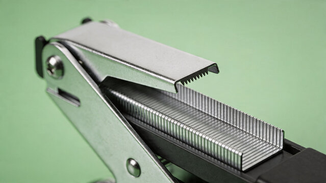 Detailed view of a silver metal stapler showing its staple loading mechanism and staples.