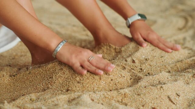 Calm shoreline with sandy extremities. Gentle seaside moment highlighting buried sandy hands. Tranquil shoreline scene portraying softly buried feet and hands in shimmering golden grains of sand