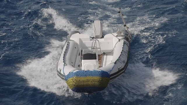 Aerial view of a rigid inflatable boat being towed and bouncing on the choppy blue sea waves