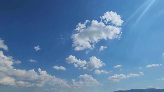 Sun Rays Piercing Through a Bright Blue Sky with White Clouds