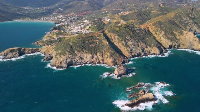 Aerial panorama of Bali coastline in Crete, Greece. Rugged rocky cliffs, turquoise bays and emerald sea with white village and mountains. Scenic Mediterranean landscape with wild shore, drone 4k.