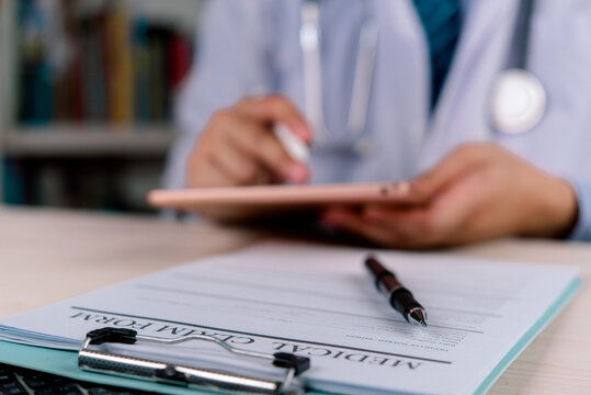 Medical claim form insurance doctor healthcare billing document hospital tablet clipboard pen desk processing patient health finance expense administration policy concept.