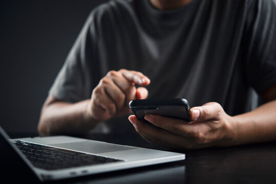 Man hands typing smartphone mobile laptop dark desk technology digital communication internet working remote late night casual online connection concept.