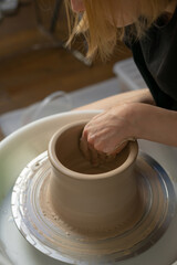 Fototapeta premium Potter shaping a clay pot on a spinning wheel. Hands covered in mud. Vertical video