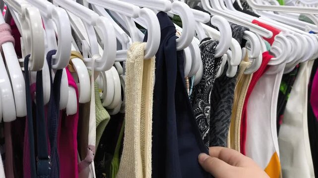 Women's hands choosing clothes from a hanger. Shopping at a second-hand store. Caring about the environment.