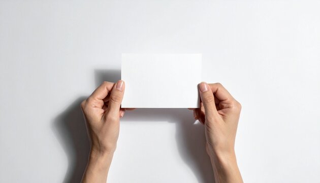 Top view of two hands holding a blank white rectangular card against a clean background perfect for mockup design and promotional messaging.