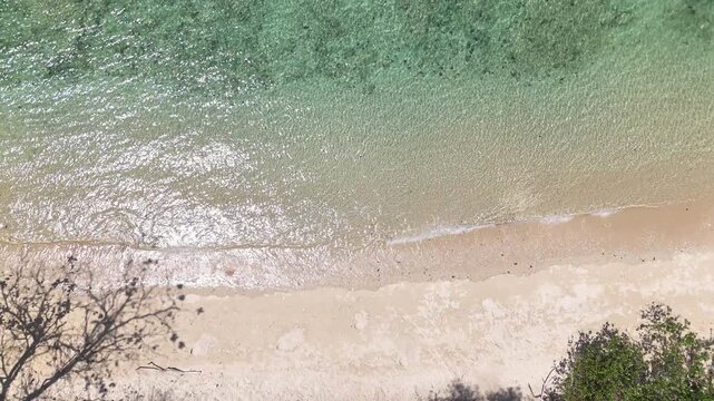 Aerial View of Serene Beach with Turquoise Water, Sandy Shore, and Lush Greenery Creating Tranquil and Relaxing Atmosphere