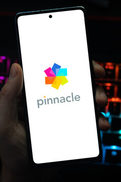 Punta Arenas, Chile &ndash; May 04, 2026: A person's hand holds a mobile smartphone displaying the colorful star-shaped Pinnacle Studio logo and brand name on a white screen, set against a dark background