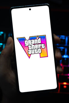 Punta Arenas, Chile &ndash; May 04, 2026: Close-up of a mobile device screen showing the GTA VI video game branding, held by a user in a dimly lit gaming environment with backlit keys