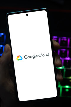 Punta Arenas, Chile &ndash; May 04, 2026: Close-up of a mobile device screen showing the Google Cloud platform icon, held by a user in a dimly lit room with glowing backlit keys