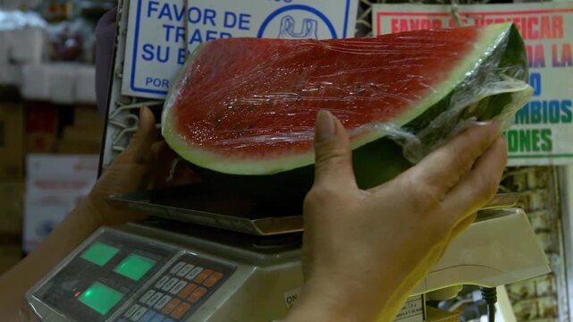 Vendedor pesando rebanada de sand&iacute;a en b&aacute;scula electr&oacute;nica en mercado local - 4K