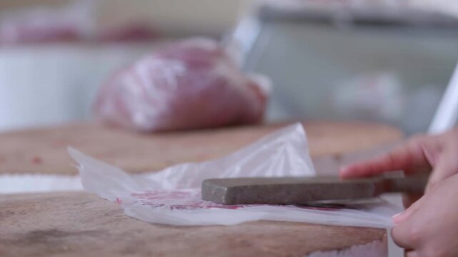 Primer plano de manos de carnicero cortando bistec de res fresco en mercado tradicional - 4K