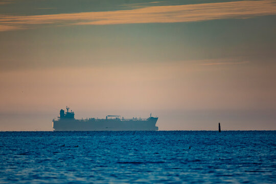 A tanker on the horizon in the fog over a calm sea at sunset