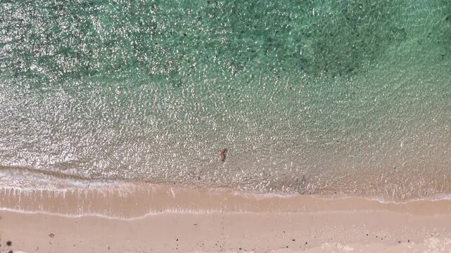 Aerial View of Serene Beach Turquoise Ocean, Gentle Waves, Sandy Shoreline, and Lone Person Enjoying Peaceful Moment
