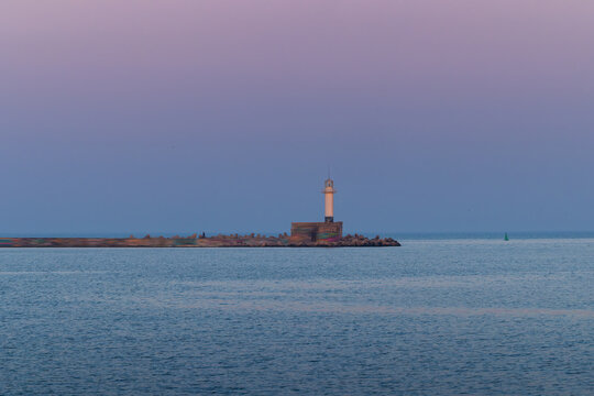 Full moon twilight landscape over sea horizon and lighting lighthouse from the coast