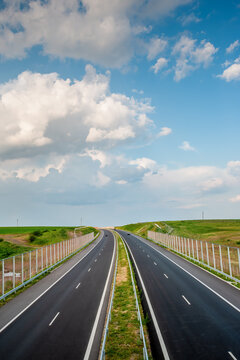 Highway road Through Green Countryside Under Blue Sky With Puffy Clouds on a sunny day, vertical aerial view