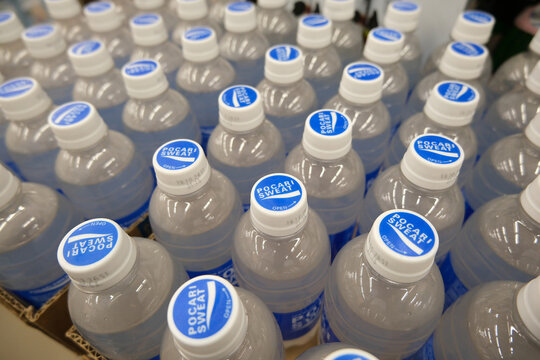 Numerous Pocari Sweat bottles, features their iconic white and blue caps arranged in a repetitive pattern. Related to mass production hydration, sports nutrition, retail inventory, beverage supplies