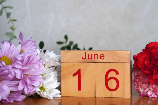 June 16. Wooden calendar with fresh flowers. Copy space.
