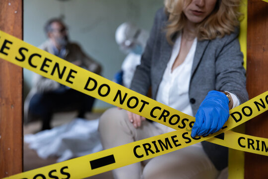 Criminal investigator wearing protective gloves working at a cordoned crime scene, collecting forensic evidence for police investigation