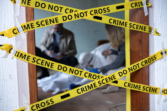 Forensic team collecting evidence at a crime scene, investigating a mystery with yellow cordon tape warning do not cross