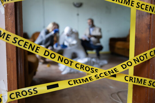 Law enforcement agents and forensic experts investigating a crime scene, focusing on analysis behind police barrier tape