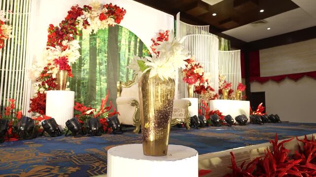 Elegant wedding stage decoration with golden flower vase and luxury floral backdrop in a banquet hall.