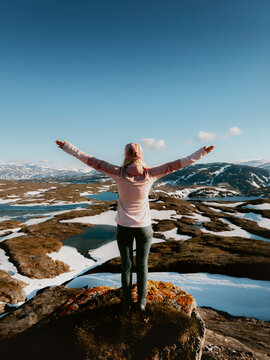 Woman tourist happy raised hands enjoying Lahko mountains view in Norway, traveler girl hiking solo outdoor active trip healthy lifestyle adventure summer vacations tour freedom harmony with nature