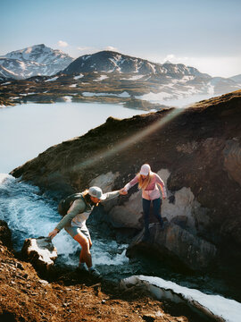 Couple man and woman hiking in Norway man helps woman crossing river in mountains travel extreme adventure lifestyle outdoor active family vacations adventure tour, friends explore Lahko national park
