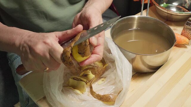 Close-up of hands peeling a potato with a sharp knife