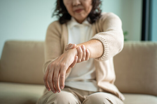 Asian elderly woman touching her wrist pain suffering from arthritis symptoms joint stiffness inflammation and chronic pain in retirement, healthcare insurance coverage for wellbeing