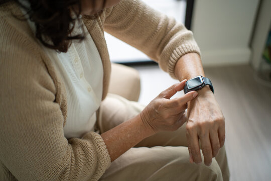 Smiling elderly woman using smartwatch for health tracking heart rate monitoring and daily activity data at home, happy senior lifestyle with technology and digital engaged in a smart retirement