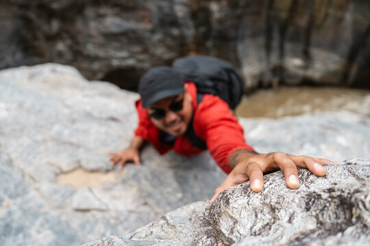 The climber had an accident after falling down the mountain. Hiker climber carefully grips a rock while scaling a steep cliff during a hike in a national park.
