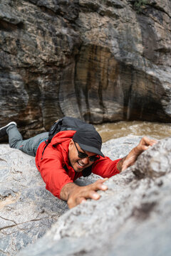 The climber had an accident after falling down the mountain. Hiker climber carefully grips a rock while scaling a steep cliff during a hike in a national park.