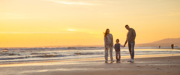 Fototapeta premium Family enjoying vacation together walking on beach at sunset